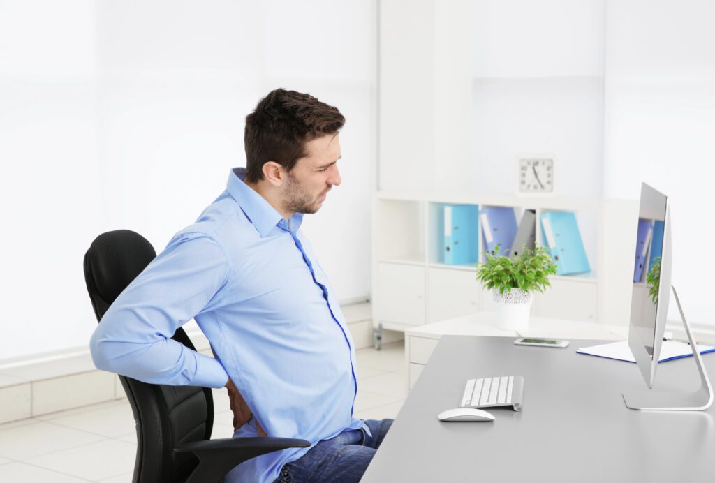 Man sitting at desk with poor posture and lower back pain, Libertyville chiropractor example