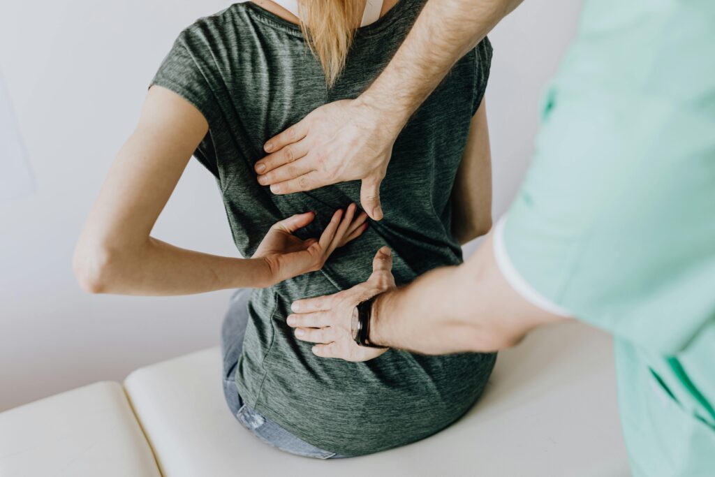 Chiropractor examining a patient’s lower back during an initial visit, demonstrating professional and focused care to identify the cause of pain before performing an adjustment.