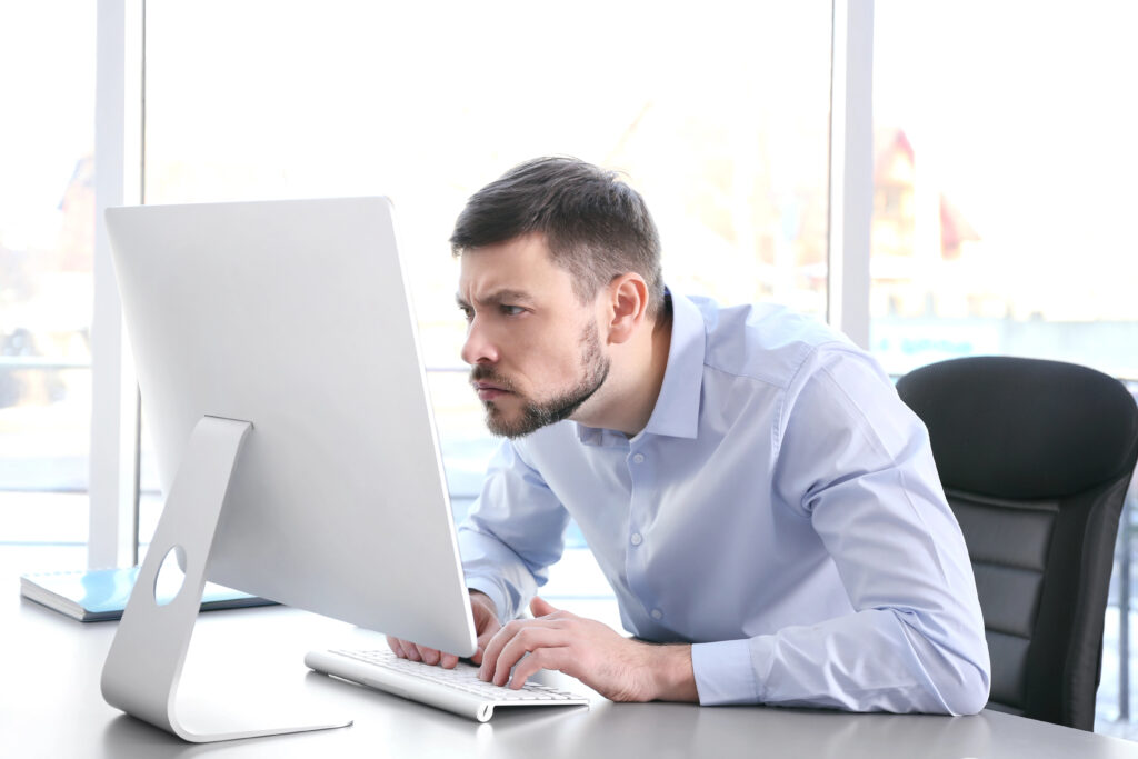 Office worker sitting at computer with forward head posture, illustrating common posture-related neck pain.